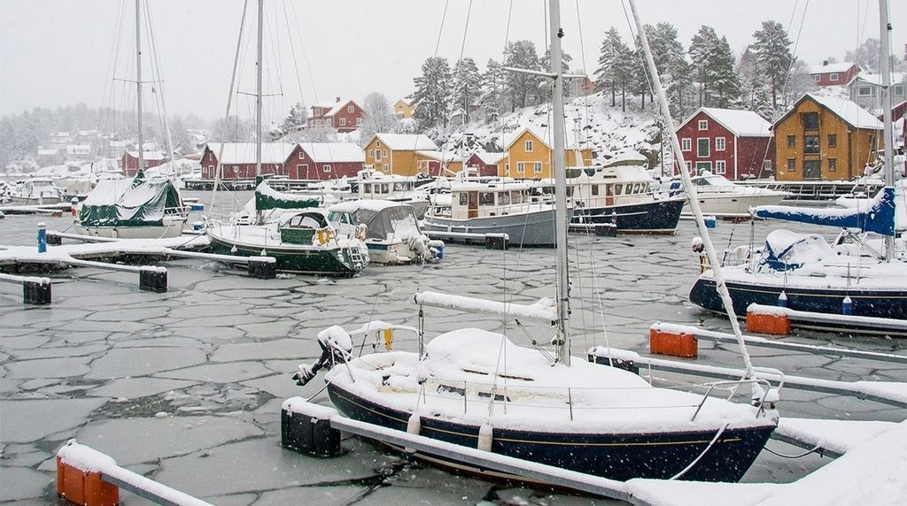 Segelboote im verschneiten Hafen zwischen Eisschollen